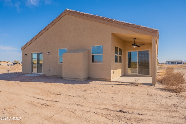 rear view of property with ceiling fan and a patio area