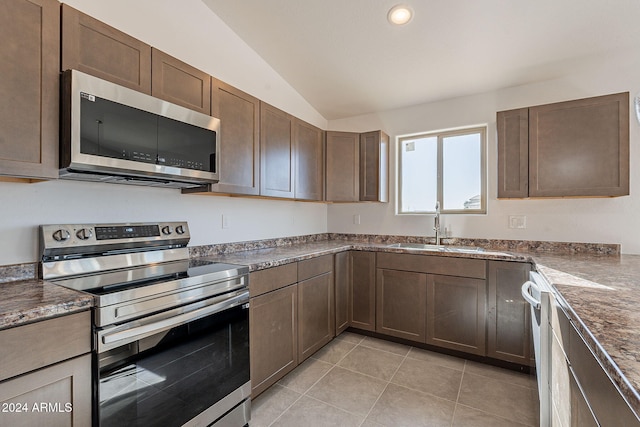 kitchen featuring lofted ceiling, sink, light tile patterned floors, appliances with stainless steel finishes, and dark brown cabinets