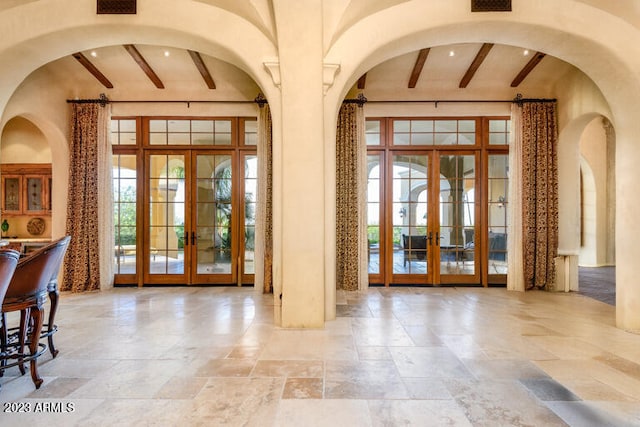 foyer featuring beam ceiling and french doors