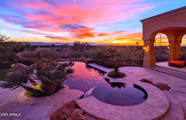 pool at dusk featuring a patio