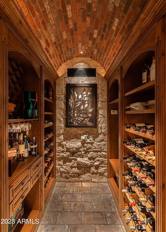 wine room featuring brick ceiling and vaulted ceiling