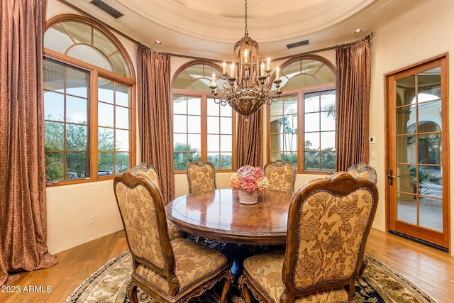 dining area with a healthy amount of sunlight, light hardwood / wood-style floors, and an inviting chandelier