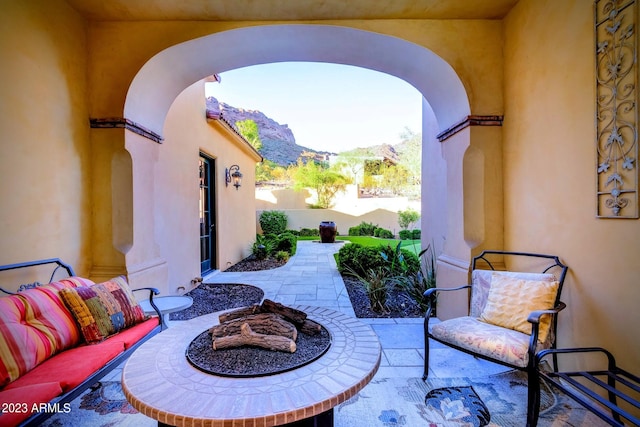 view of patio with a mountain view and an outdoor living space with a fire pit