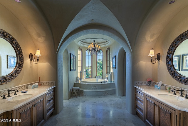 bathroom featuring vanity, an inviting chandelier, a bath, and vaulted ceiling