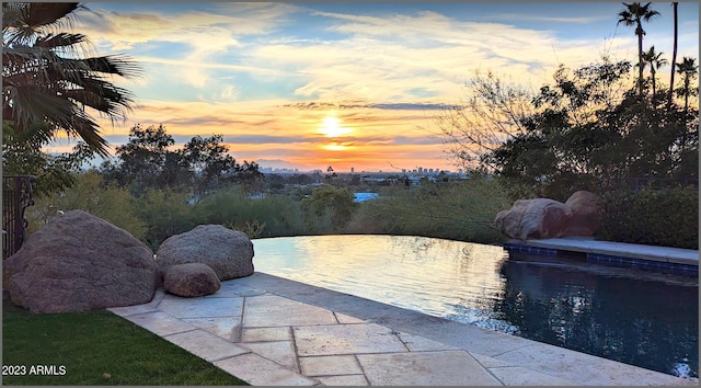 pool at dusk featuring a patio