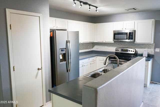 kitchen with track lighting, tasteful backsplash, stainless steel appliances, sink, and white cabinetry