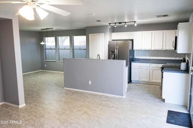 kitchen with stainless steel fridge, backsplash, ceiling fan, white cabinetry, and hanging light fixtures