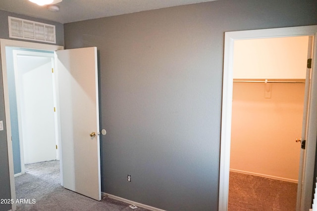 unfurnished bedroom featuring carpet flooring, a spacious closet, and a closet