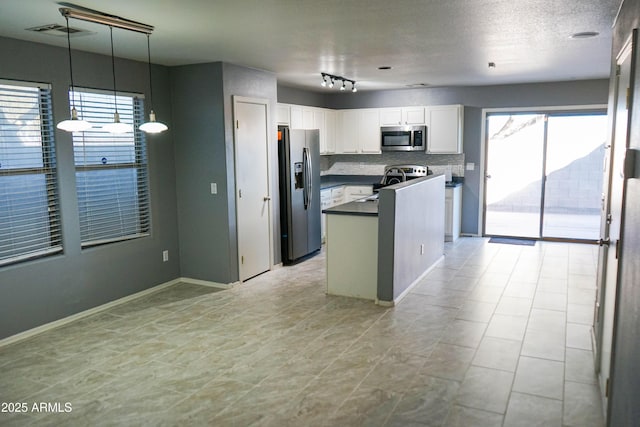 kitchen with white cabinets, decorative backsplash, a textured ceiling, decorative light fixtures, and stainless steel appliances