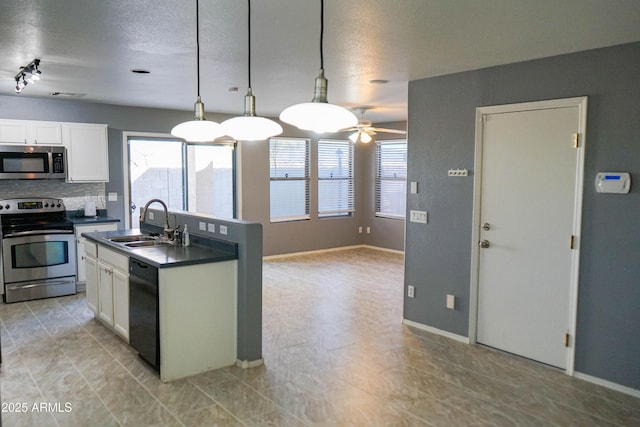 kitchen with appliances with stainless steel finishes, a healthy amount of sunlight, sink, decorative light fixtures, and white cabinets