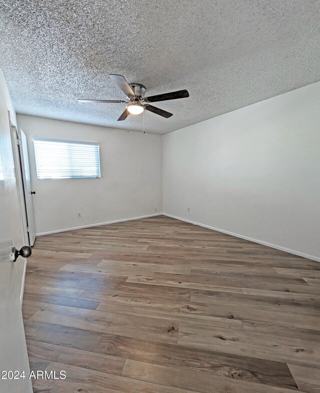 empty room featuring a textured ceiling, hardwood / wood-style flooring, and ceiling fan