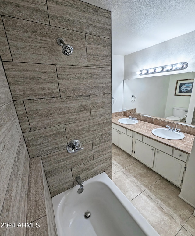 full bathroom with tile patterned floors, vanity, a textured ceiling, toilet, and tiled shower / bath