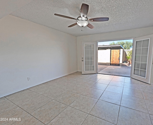 tiled empty room featuring ceiling fan, french doors, and a textured ceiling