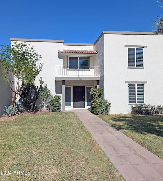 view of front of house featuring a balcony and a front yard