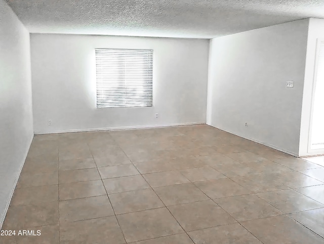 unfurnished room with light tile patterned floors and a textured ceiling