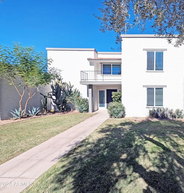 view of front of house with a balcony and a front lawn