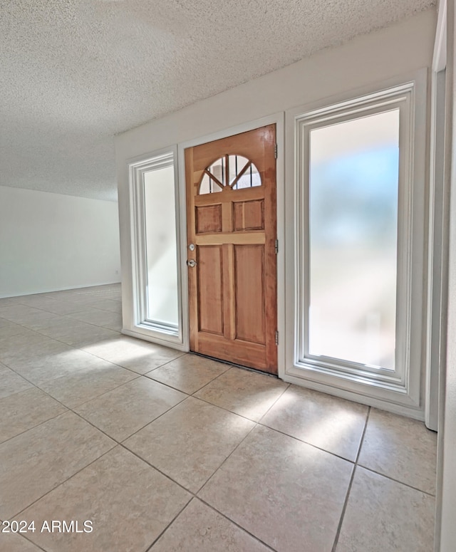 entryway with light tile patterned floors and a textured ceiling