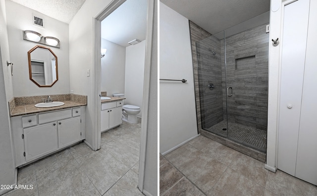 bathroom with a textured ceiling, vanity, an enclosed shower, and toilet