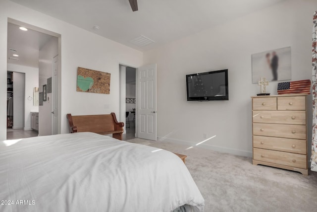 carpeted bedroom with ensuite bathroom and ceiling fan