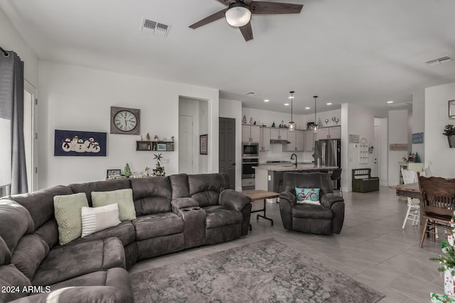 living room featuring sink, ceiling fan, and light tile patterned flooring