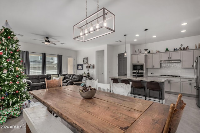 tiled dining space featuring ceiling fan with notable chandelier and sink