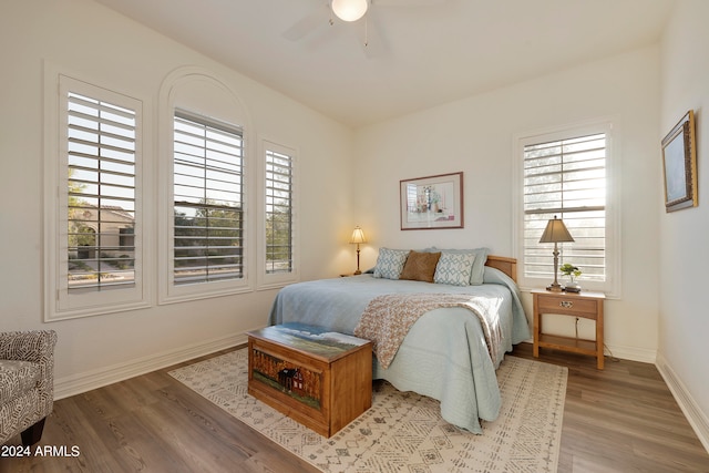 bedroom with multiple windows, wood-type flooring, and ceiling fan