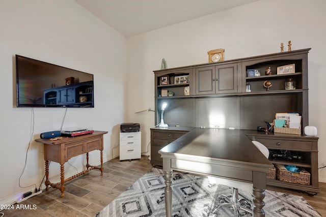 home office featuring lofted ceiling and light hardwood / wood-style floors