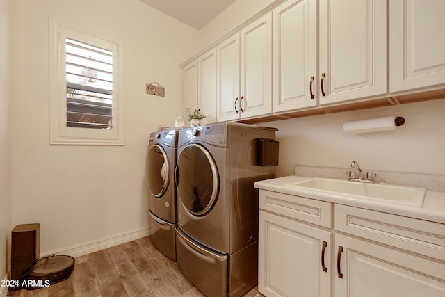 laundry room with washer and clothes dryer, cabinets, light wood-type flooring, and sink