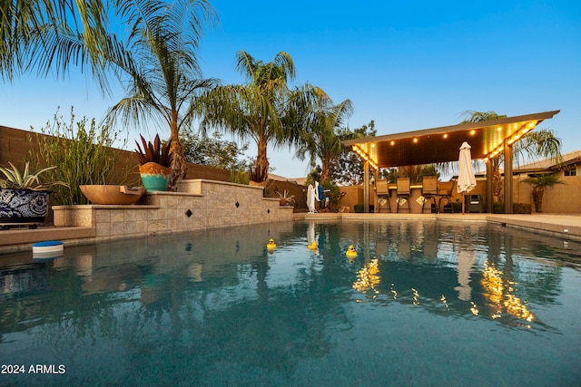 pool at dusk featuring a patio area