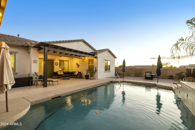 pool at dusk with a patio area and an outdoor hangout area