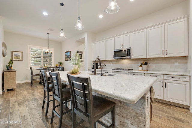 kitchen featuring an island with sink, white cabinets, light hardwood / wood-style floors, and appliances with stainless steel finishes