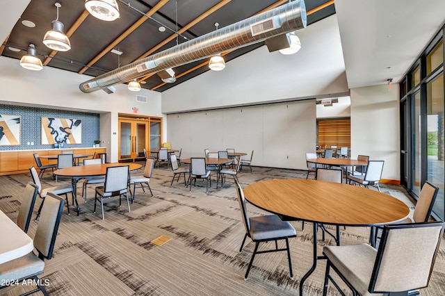 dining room with high vaulted ceiling and light colored carpet