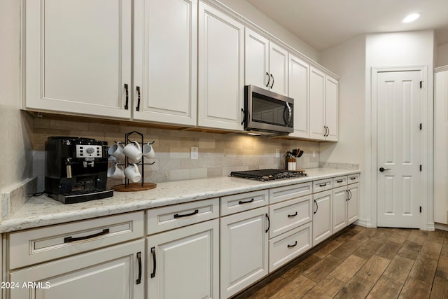 kitchen featuring appliances with stainless steel finishes, light stone countertops, white cabinetry, and dark hardwood / wood-style floors