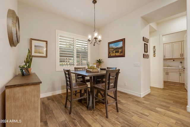 dining room with light wood-type flooring, sink, and a chandelier