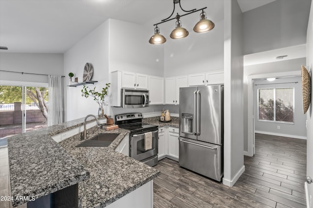 kitchen featuring dark stone countertops, white cabinetry, stainless steel appliances, and decorative light fixtures