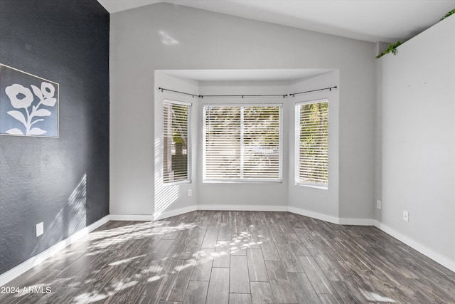 spare room featuring wood-type flooring and vaulted ceiling