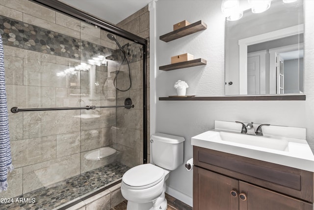 bathroom featuring vanity, toilet, and a shower with door