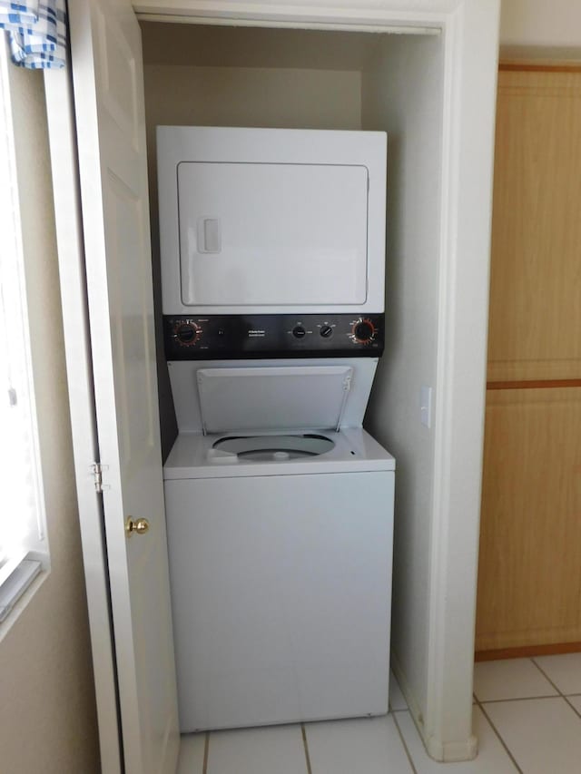 laundry room featuring tile patterned floors and stacked washer and dryer