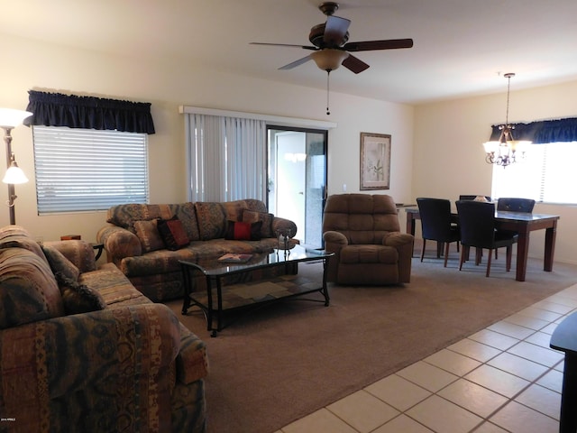 living area featuring light tile patterned floors, light colored carpet, and ceiling fan with notable chandelier