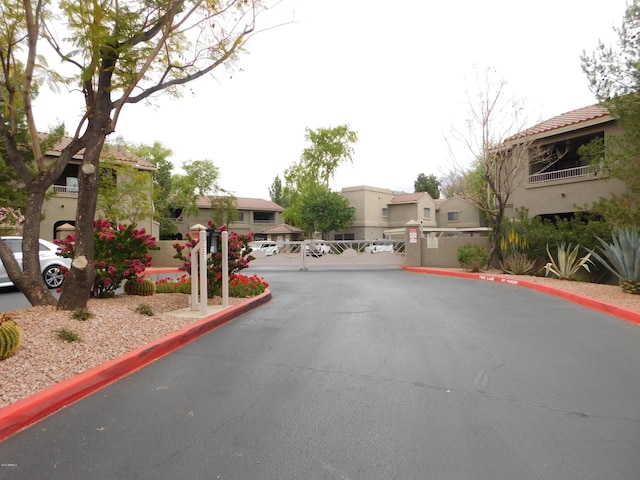 view of road featuring a gated entry, a residential view, curbs, and a gate