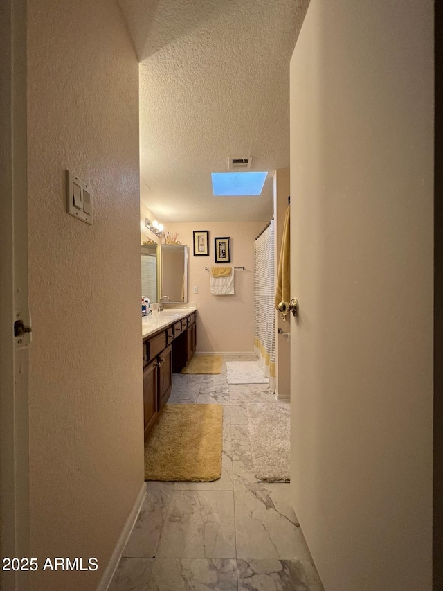 9060 N 47th Ln, Glendale, AZ 85302 - bathroom featuring a textured ceiling, a skylight, vanity, curtained shower, and baseboards