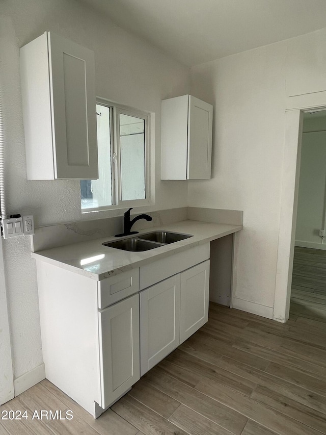 kitchen featuring white cabinetry, sink, and light hardwood / wood-style flooring