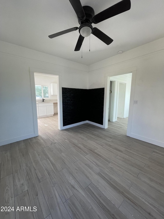 empty room with ceiling fan and light hardwood / wood-style flooring