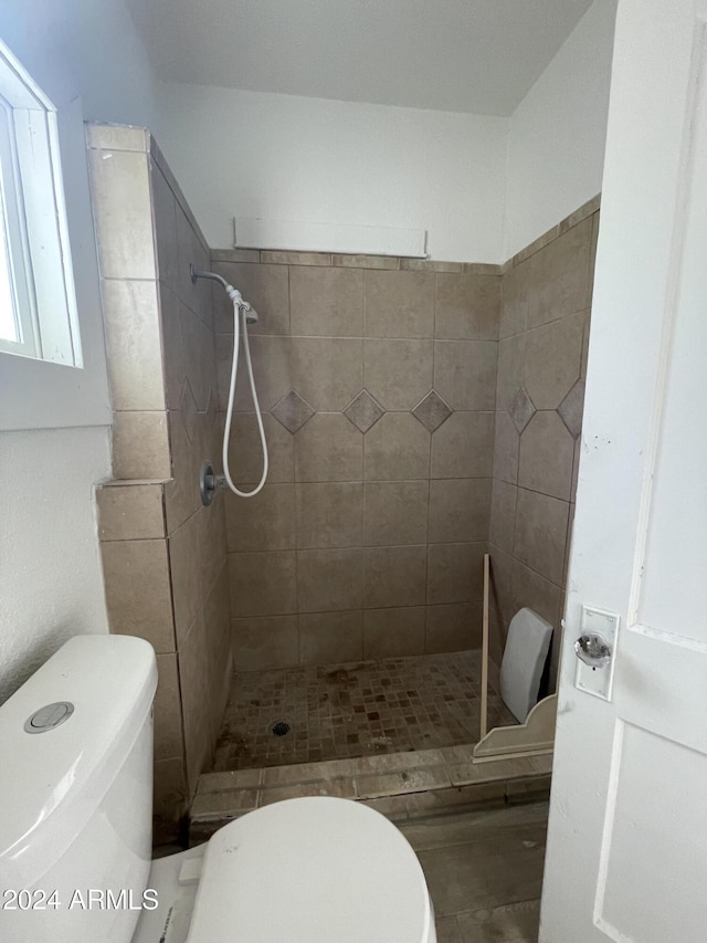 bathroom featuring tiled shower and toilet