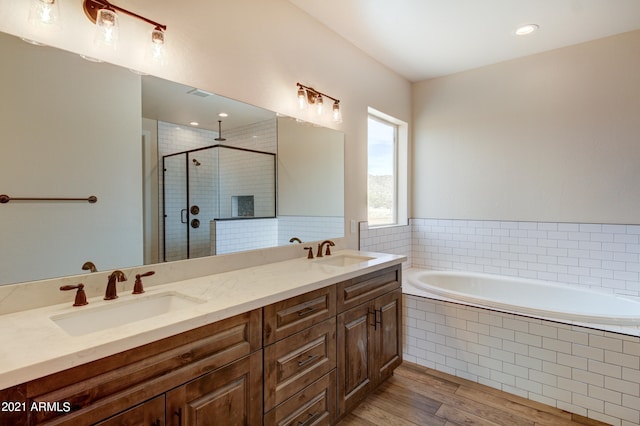 bathroom featuring double sink, independent shower and bath, oversized vanity, and wood-type flooring