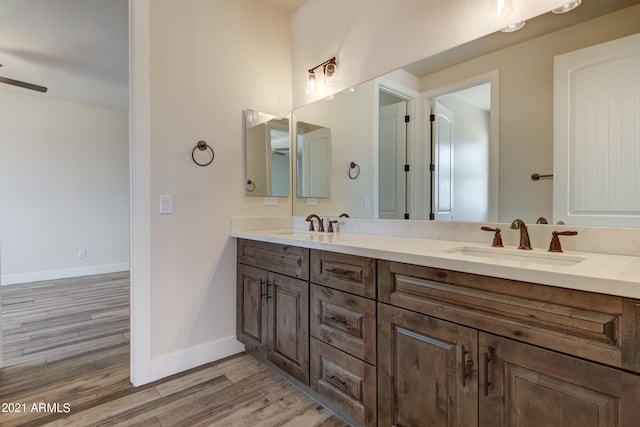 bathroom with ceiling fan, wood-type flooring, double sink, and vanity with extensive cabinet space