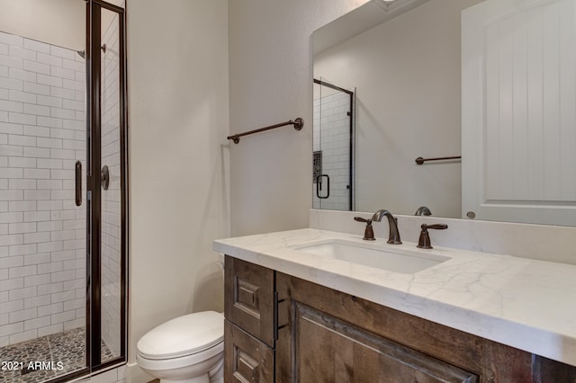 bathroom featuring toilet, vanity, and a shower with shower door