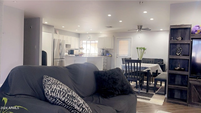 living room with ceiling fan, sink, and dark wood-type flooring