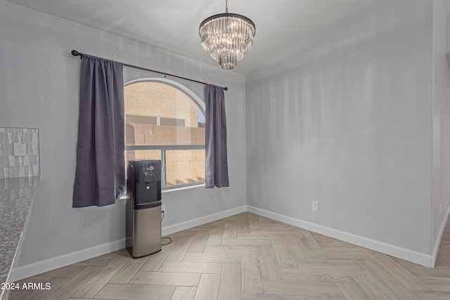 spare room with an inviting chandelier and light parquet floors