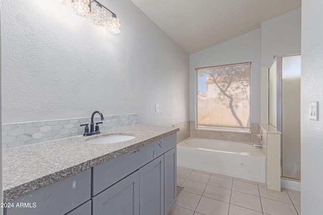 bathroom featuring backsplash, tile patterned floors, vanity, lofted ceiling, and a bathing tub